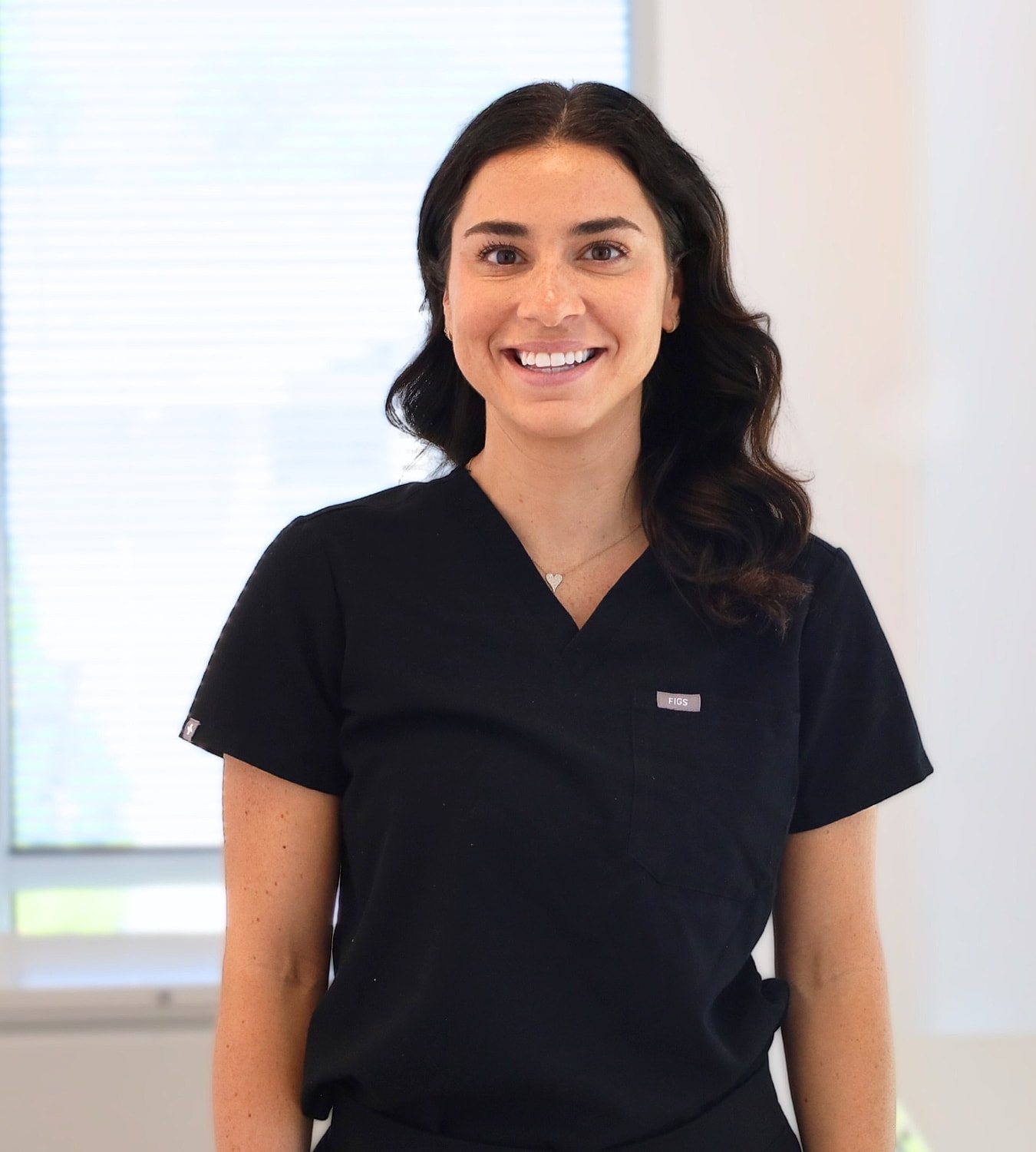 Smiling professional in black medical scrubs.
