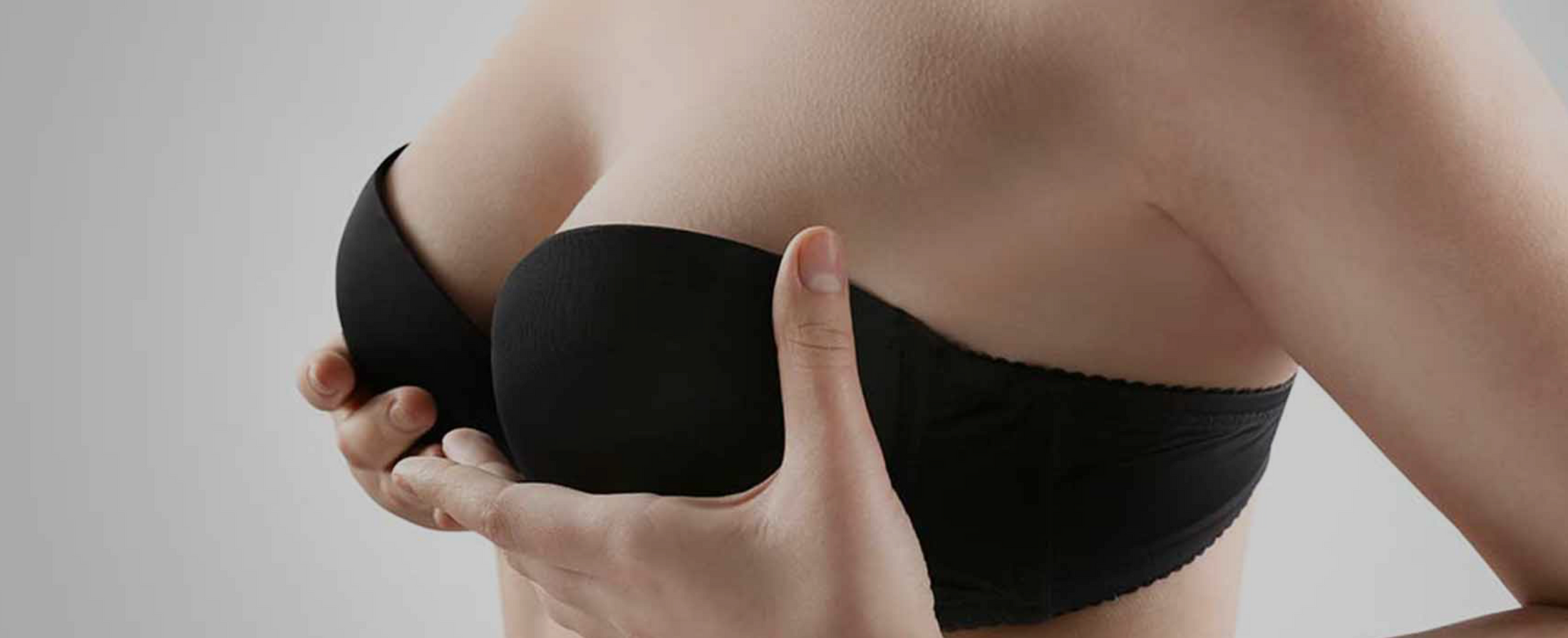 Person adjusting a black strapless bra.