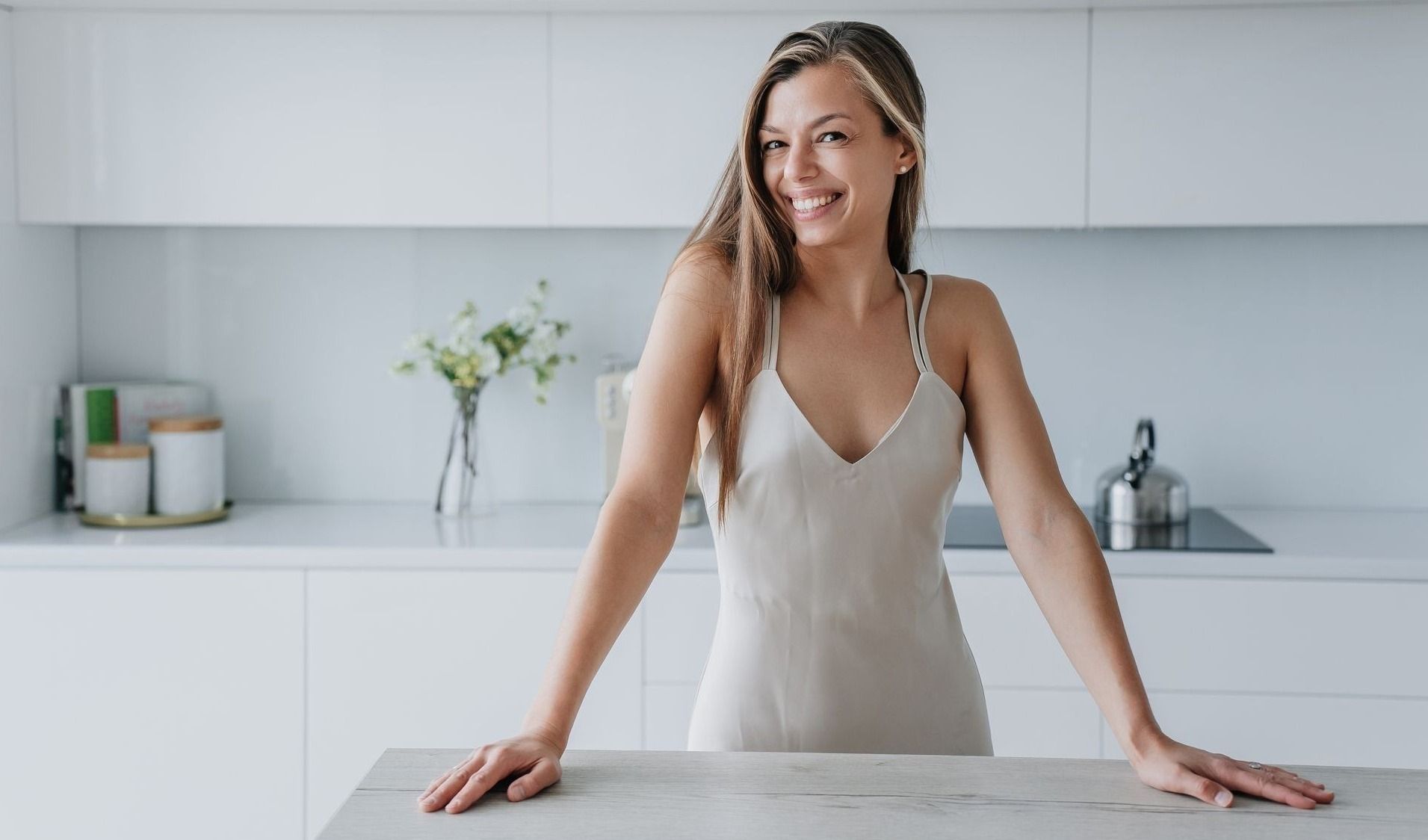 Smiling woman in a modern kitchen setting.