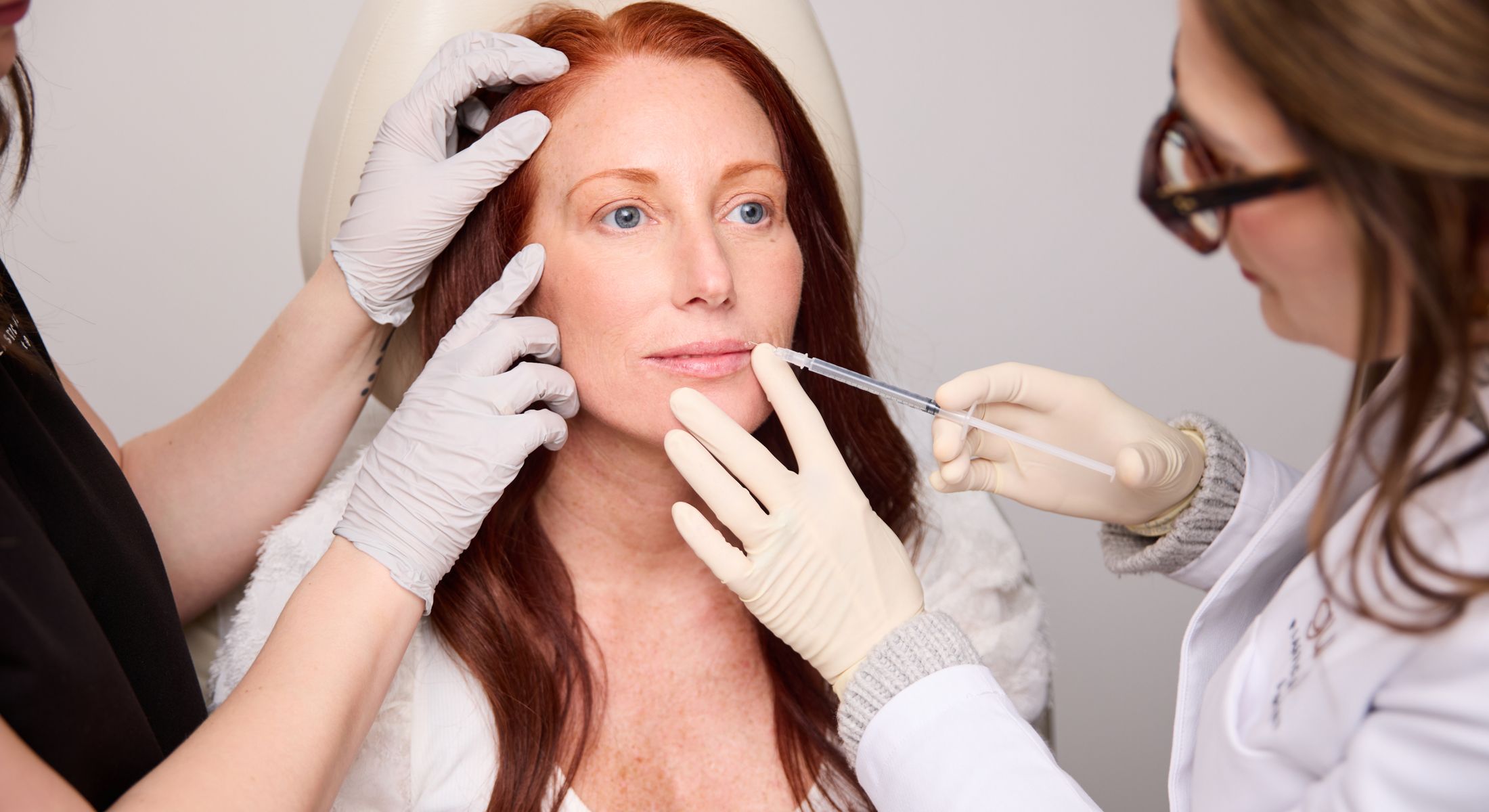 Woman receiving cosmetic treatment in clinic setting.