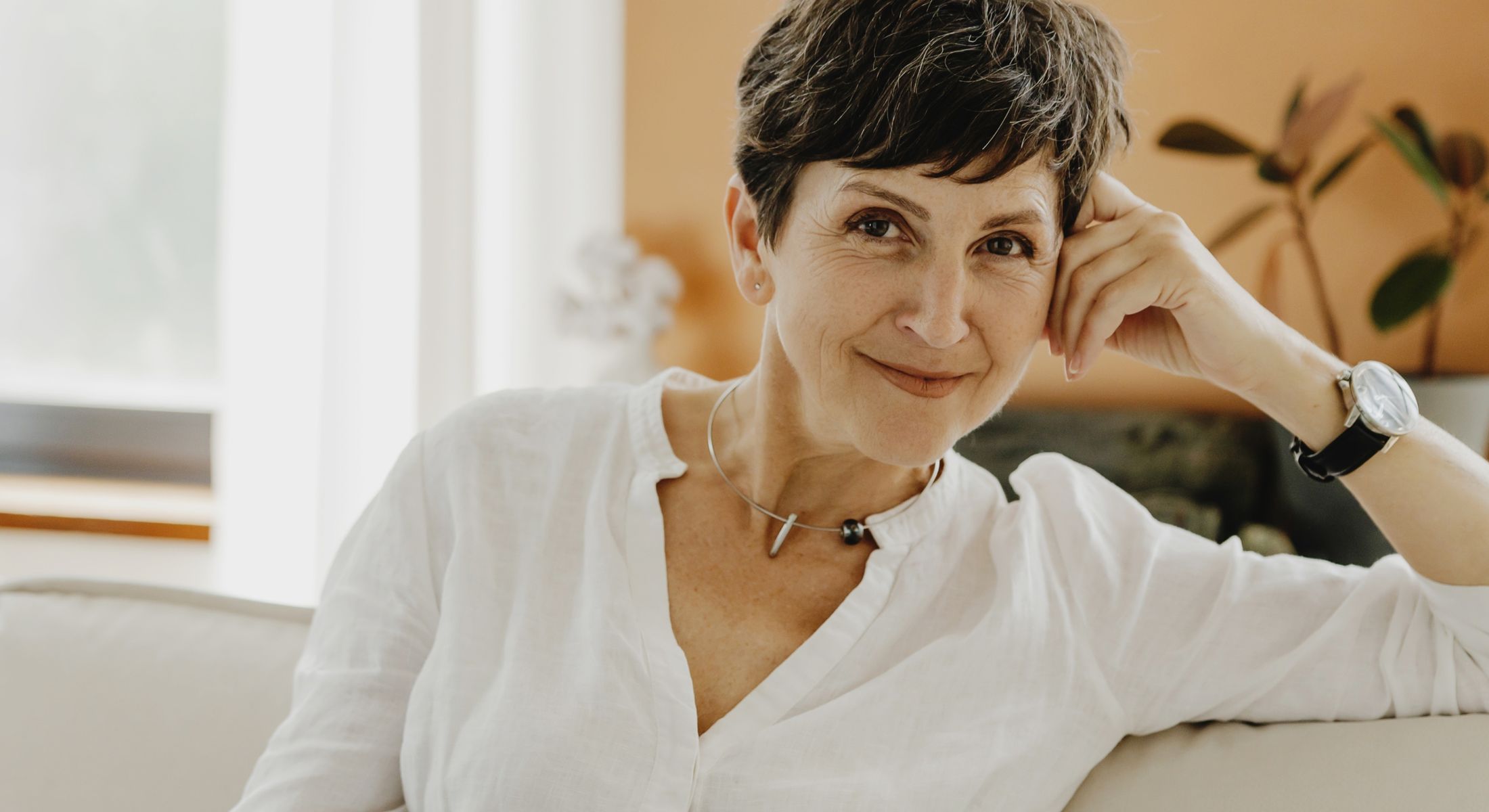 Smiling woman sitting on a sofa indoors.