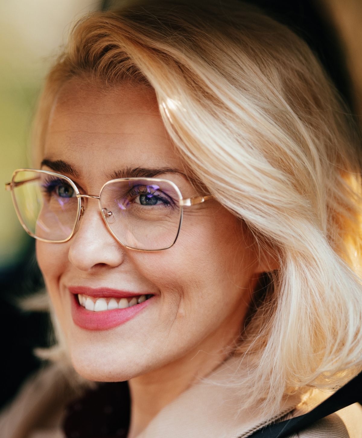 Smiling woman with glasses and blonde hair.